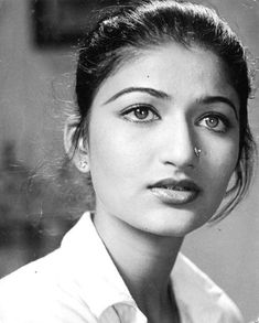 an old black and white photo of a woman wearing a collared shirt looking at the camera