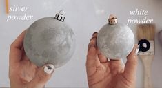 two hands holding silver and white christmas ornaments