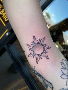 a person with a tattoo on their arm and the sun in the middle of it