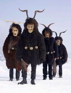 three men in horned costumes standing in the snow