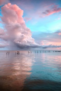 the sky is pink and blue as it reflects in the calm water on an overcast day