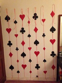 a wall decorated with playing card suits and red string hanging from it's sides