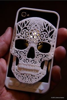 a hand holding a cell phone with a white skull on it's back cover