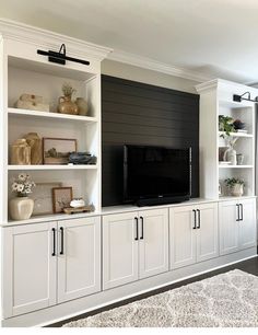 a living room with white cabinets and black tv mounted on it's side wall