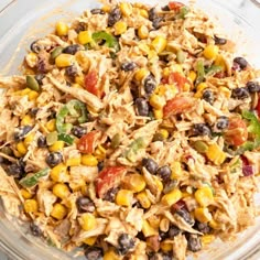 a glass bowl filled with chicken salad and black beans, corn, tomatoes, green peppers