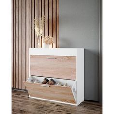 a white and wood shoe cabinet with two drawers on the bottom, next to a plant in a vase