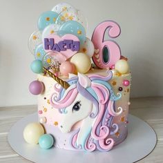 a unicorn birthday cake with balloons and confetti on the top is decorated in pastel colors