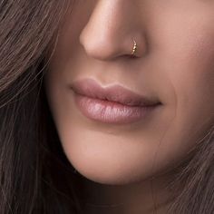 a close up shot of a woman's face with her nose piercing in gold