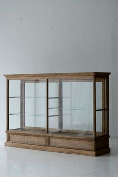 a wooden display case with glass shelves on the top and bottom, in front of a white wall