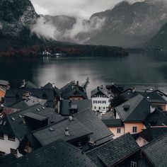 an aerial view of houses and mountains in the foggy day with water below them