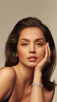 a woman with her hand on her face and wearing a bracelet, posing for the camera