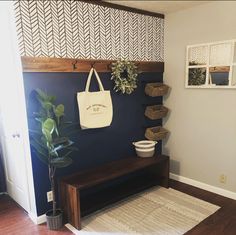 a wooden bench sitting in front of a wall with baskets on it and a tote bag hanging from the back