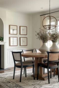 a dining room table with four chairs and a vase on top of it in front of a fireplace