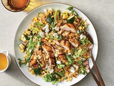 a white plate topped with chicken, corn and feta salad next to a glass of beer