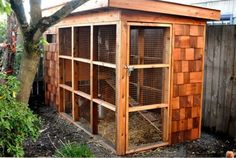 an outdoor chicken coop with wooden walls and doors, surrounded by plants in the back yard