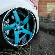 a white car with blue wheels parked on the side of the road in front of a brick building