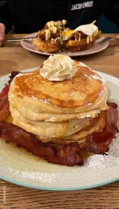 a stack of pancakes on a plate with bacon