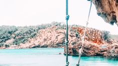 there is a rope hanging from the side of a boat in the water near some rocks