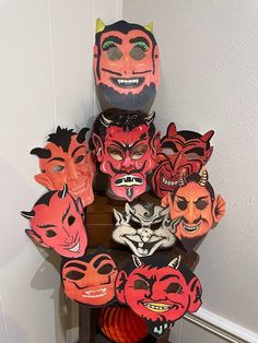 a group of masks sitting on top of a wooden table next to a wall with white walls