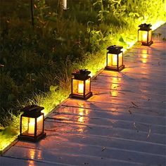 some lights that are on the side of a path in the grass and one is lit up