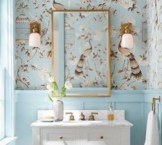 a bathroom decorated in blue and white with gold trimmings on the wall, two mirrors above the sink