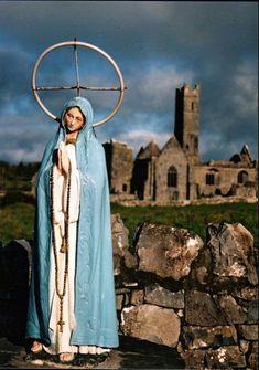 a woman dressed in blue and holding a cross