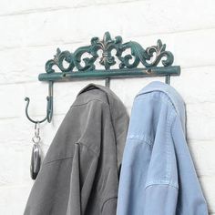 an iron coat rack with two coats hanging on it