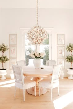 a dining room table with white chairs and a chandelier