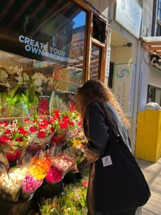 a woman walking past a flower shop with lots of flowers