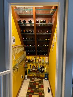 an open door leading to a wine cellar with bottles and glasses on the shelves above