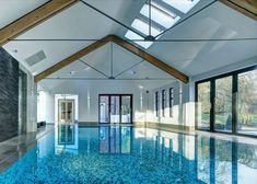 an indoor swimming pool with skylights and glass doors leading to the upper floor area