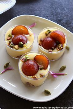 three desserts are arranged on a white plate with pink flowers and leaves around them