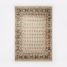 a beige and black area rug with an intricate design in the center on a white wall