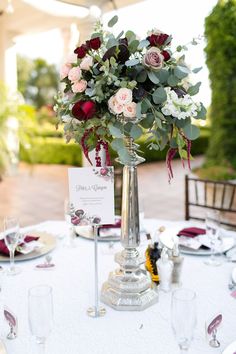 a table set up for a formal dinner with flowers in a vase and place cards