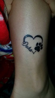 a small tattoo on the ankle of a person with a heart and dog paw in it