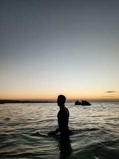 a person standing in the water at sunset