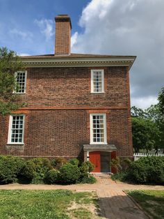 an old brick building with white windows and red door