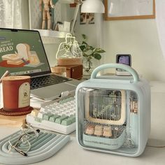 an open laptop computer sitting on top of a desk next to a toaster and keyboard