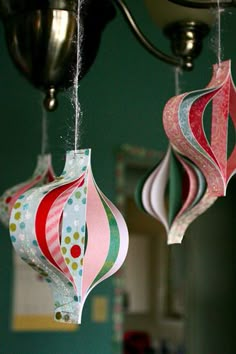 three paper ornaments hanging from a chandelier