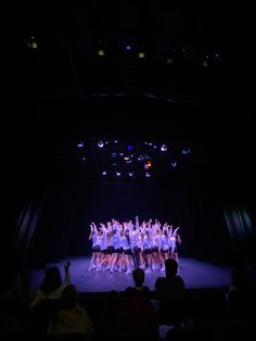 a group of people standing on top of a stage with their arms in the air