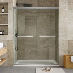 a bathroom with a walk in shower next to a white sink and towel on the floor