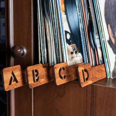 three wooden blocks with the letters abc and d are hanging on a wall next to records