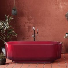 a red bath tub sitting on top of a tiled floor