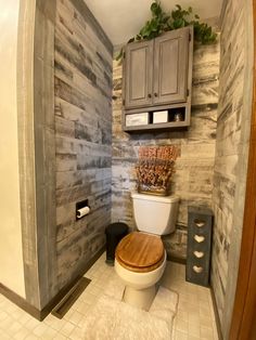 a bathroom with a toilet, cabinet and plants in the corner on the counter top