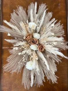 dried flowers and feathers are arranged on a wooden table in front of a framed photograph