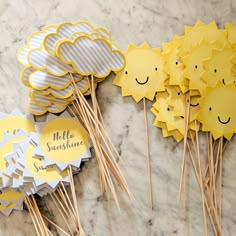 yellow and white cupcake toppers with smiley faces on them sitting on a marble surface