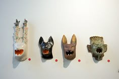 five animal masks are lined up on the wall, each with different shapes and sizes