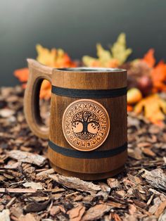 a wooden mug sitting on top of wood chips with a tree in the middle and an inscription underneath it