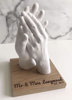 a white ceramic hand is on top of a wooden block with the words mr and mrs langman