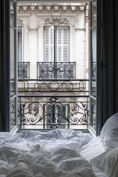 an open balcony door leading to a bed with white sheets